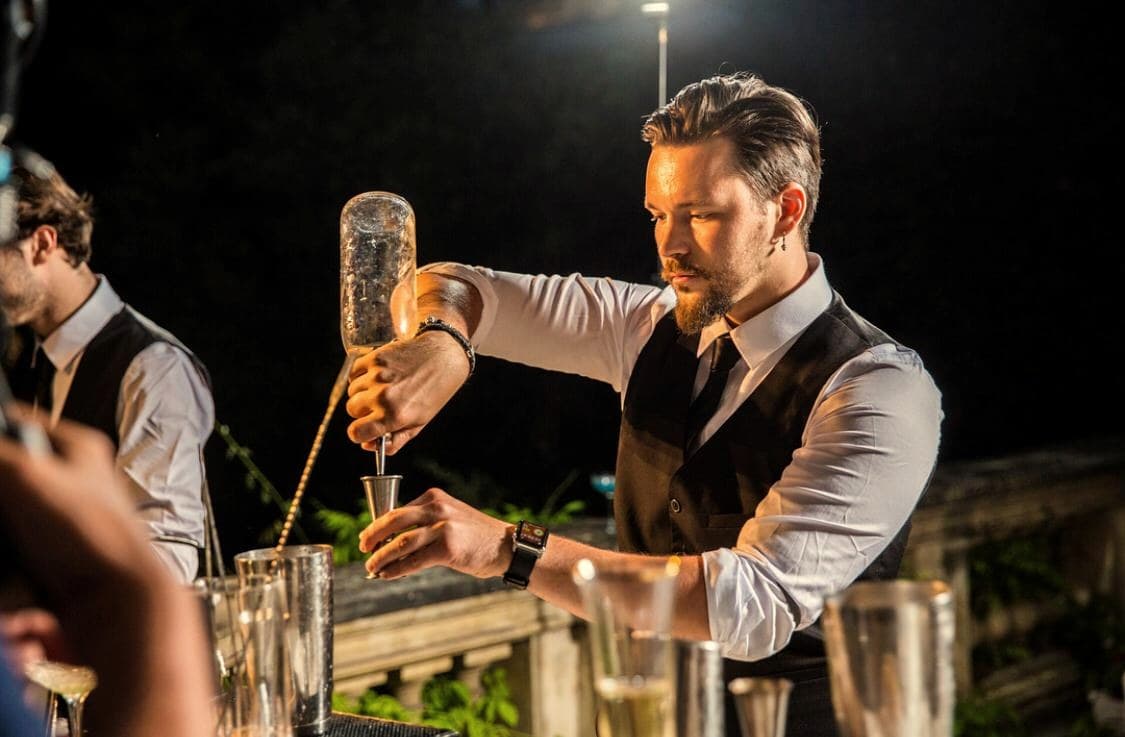 Mixologue Maison Zlato dosant un cocktail au jigger lors d'une soirée